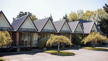 Uma fileira de edifícios modernos com telhados triangulares, um pátio central e pequenas árvores.