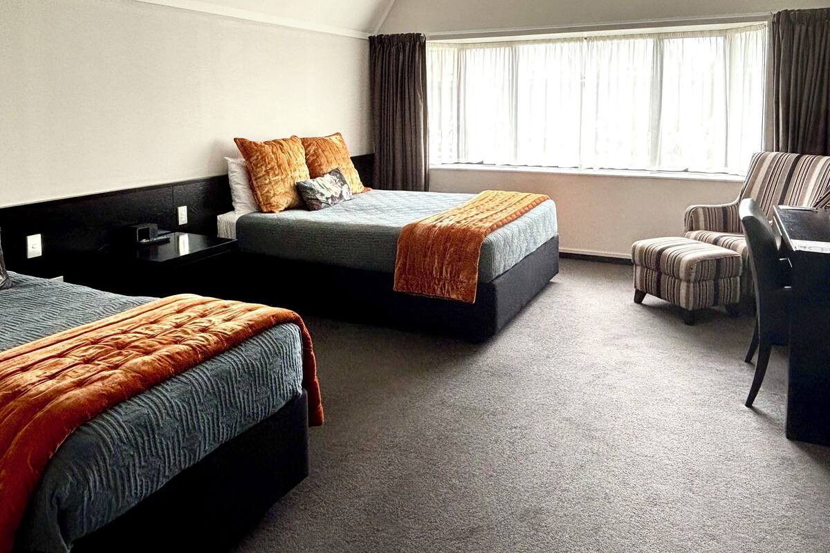 A hotel room with two beds, a desk, and a chair.