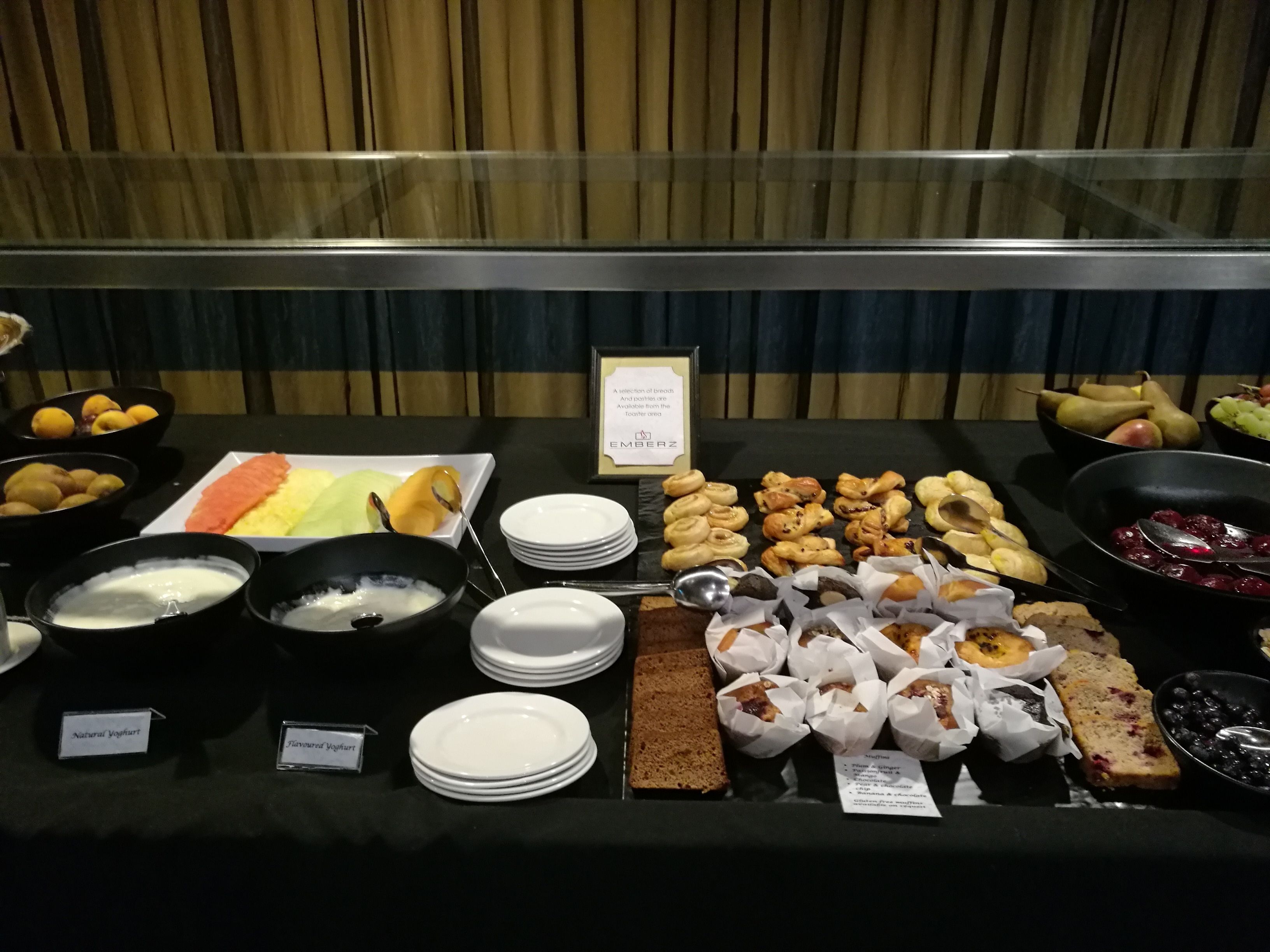 Un bufé con diversos alimentos, entre ellos pasteles, frutas y productos lácteos.