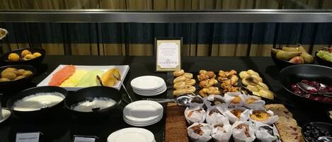 Un bufé con diversos alimentos, entre ellos pasteles, frutas y productos lácteos.