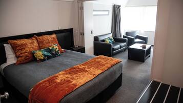 A hotel room with a large bed, a sofa, a coffee table, and a view of the outside.
