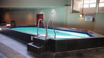 An indoor swimming pool with steps and metal railings.