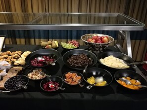 Una mesa de buffet con diversos alimentos, incluyendo frutas, verduras y platos preparados.