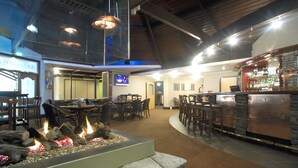 A restaurant with a stone fire feature, wooden tables, and a bar area. - Ascot Park Hotel (Invercargill)