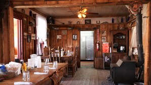 A rustic wooden dining area with a long table, chairs, and a ceiling fan.