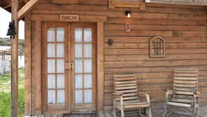 A wooden cabin with a sign reading "Duncan" above the door, two wooden chairs outside, and a cow skull decoration on the wall.