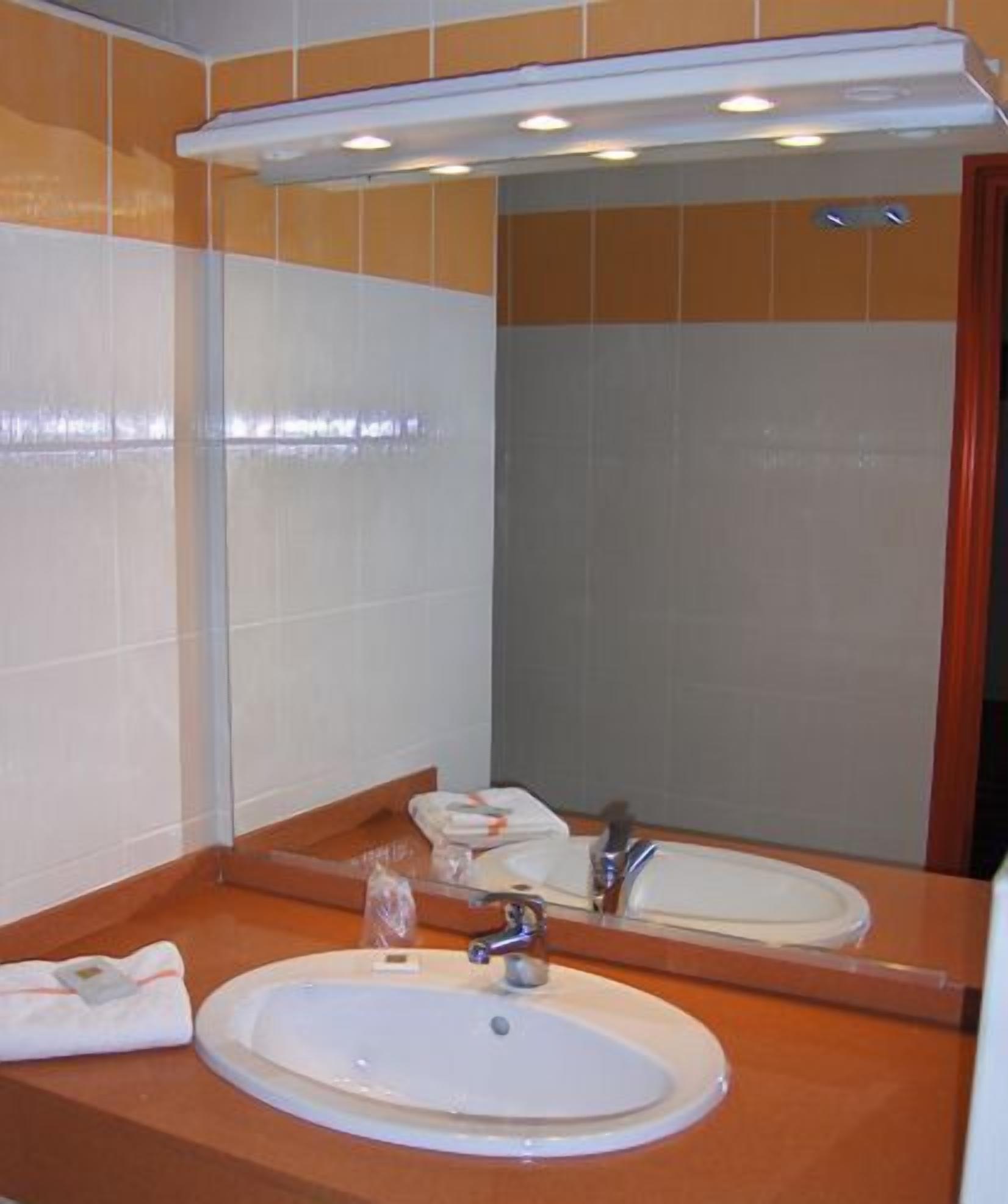 A bathroom with a white sink, a mirror, and a towel rack.