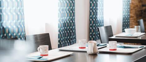 A conference room with a long table, chairs, and coffee mugs.