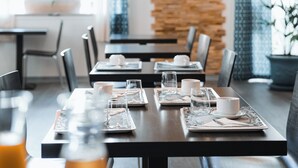 A restaurant with a long table set for dining, a stone wall, and hanging pendant lights. - urban by balladins Perpignan (Perpignan)