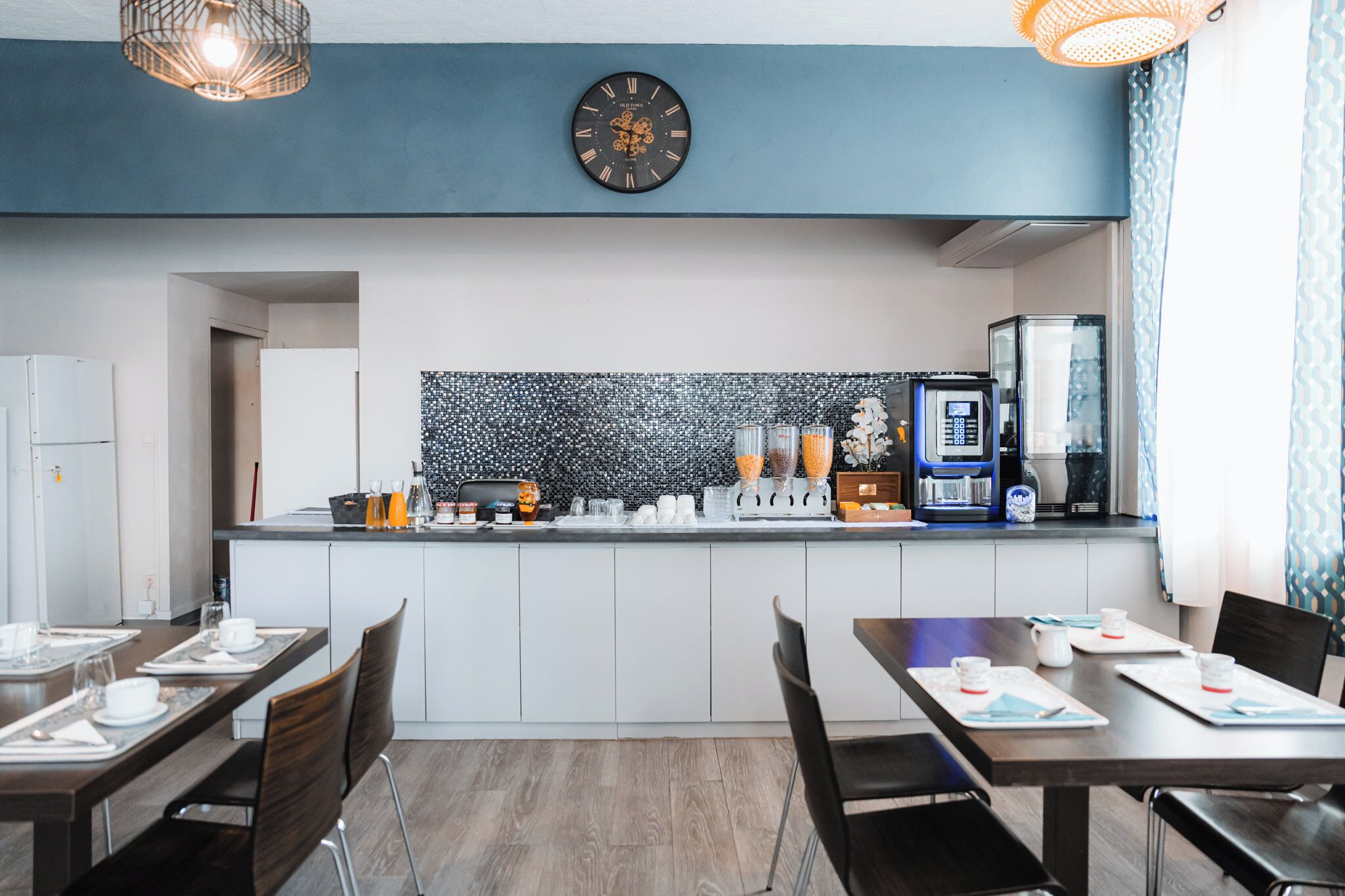 A modern kitchen with a clock, coffee machine, and a tiled backsplash.