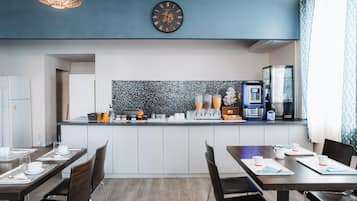 A modern kitchen with a clock, coffee machine, and a tiled backsplash.