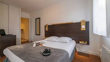 Ein Hotelzimmer mit einem großen Bett, Nachttischen, einem Schreibtisch mit einem Laptop und einem Kleiderschrank.