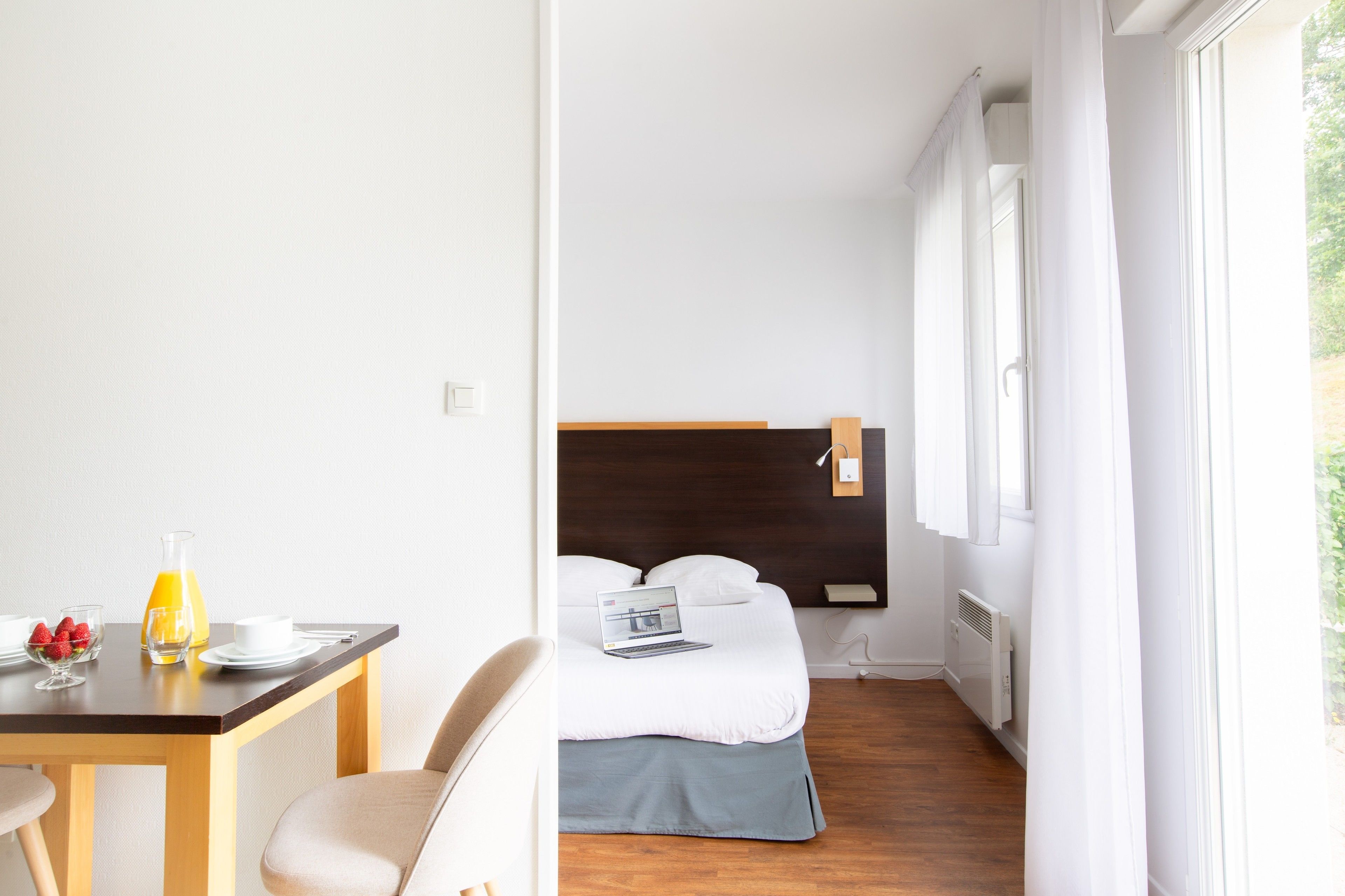 Une chambre d’hôtel avec un lit, un bureau avec des articles pour le petit-déjeuner et un ordinateur portable.