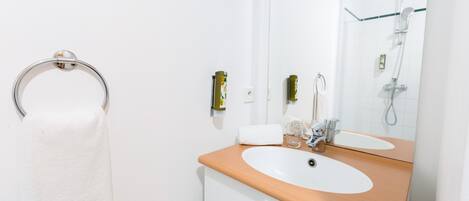 Une salle de bain avec un plan de toilette en bois, un lavabo blanc et une cabine de douche en verre.