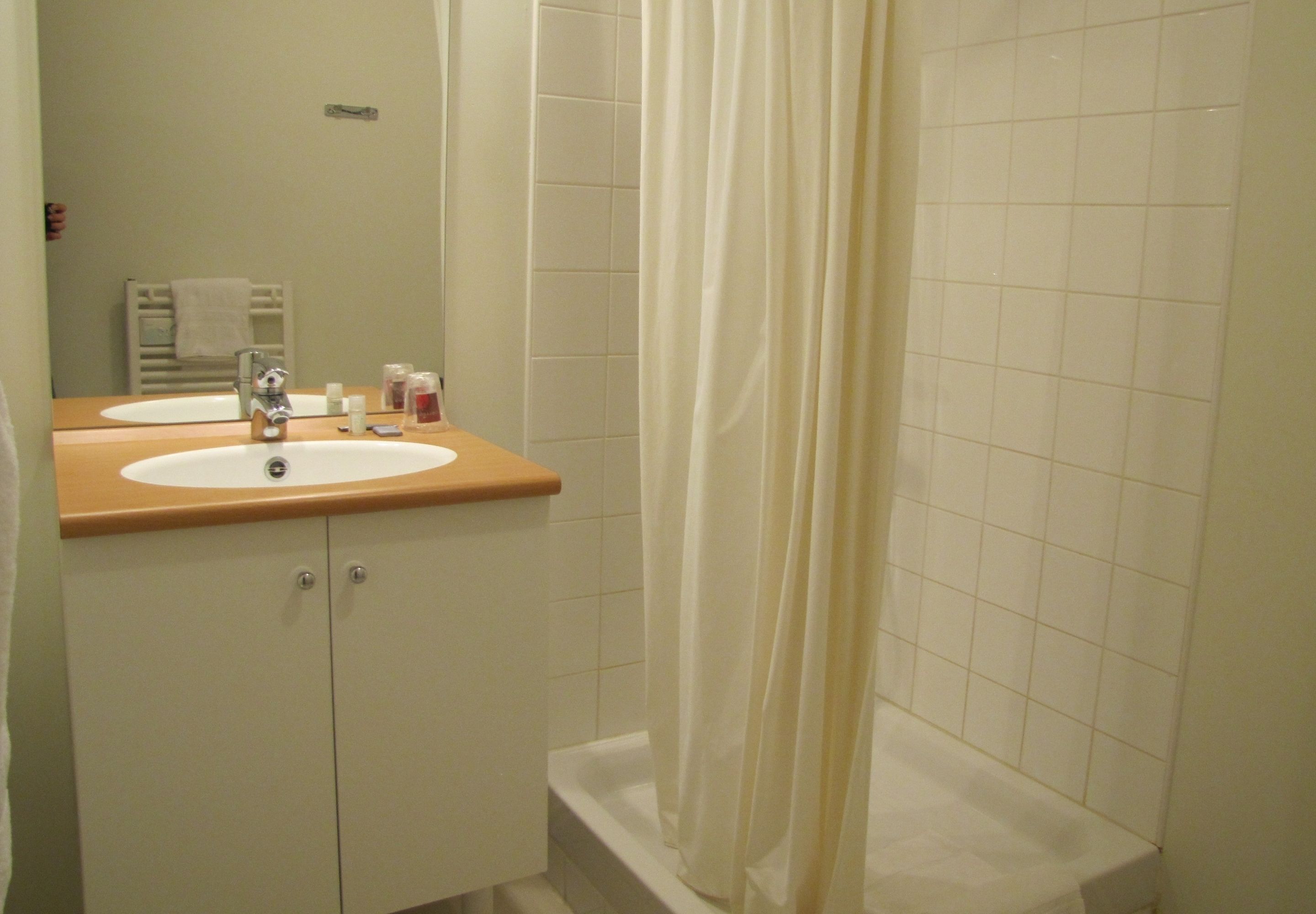 A bathroom with two sinks, a shower, and a towel rack.
