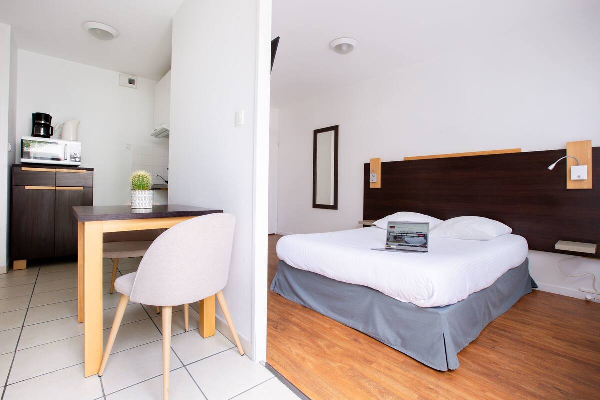 Un dormitorio con cama, mesita de noche y escritorio con silla.