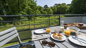 Desayuno dispuesto en una mesa al aire libre con vistas a un paisaje verde.