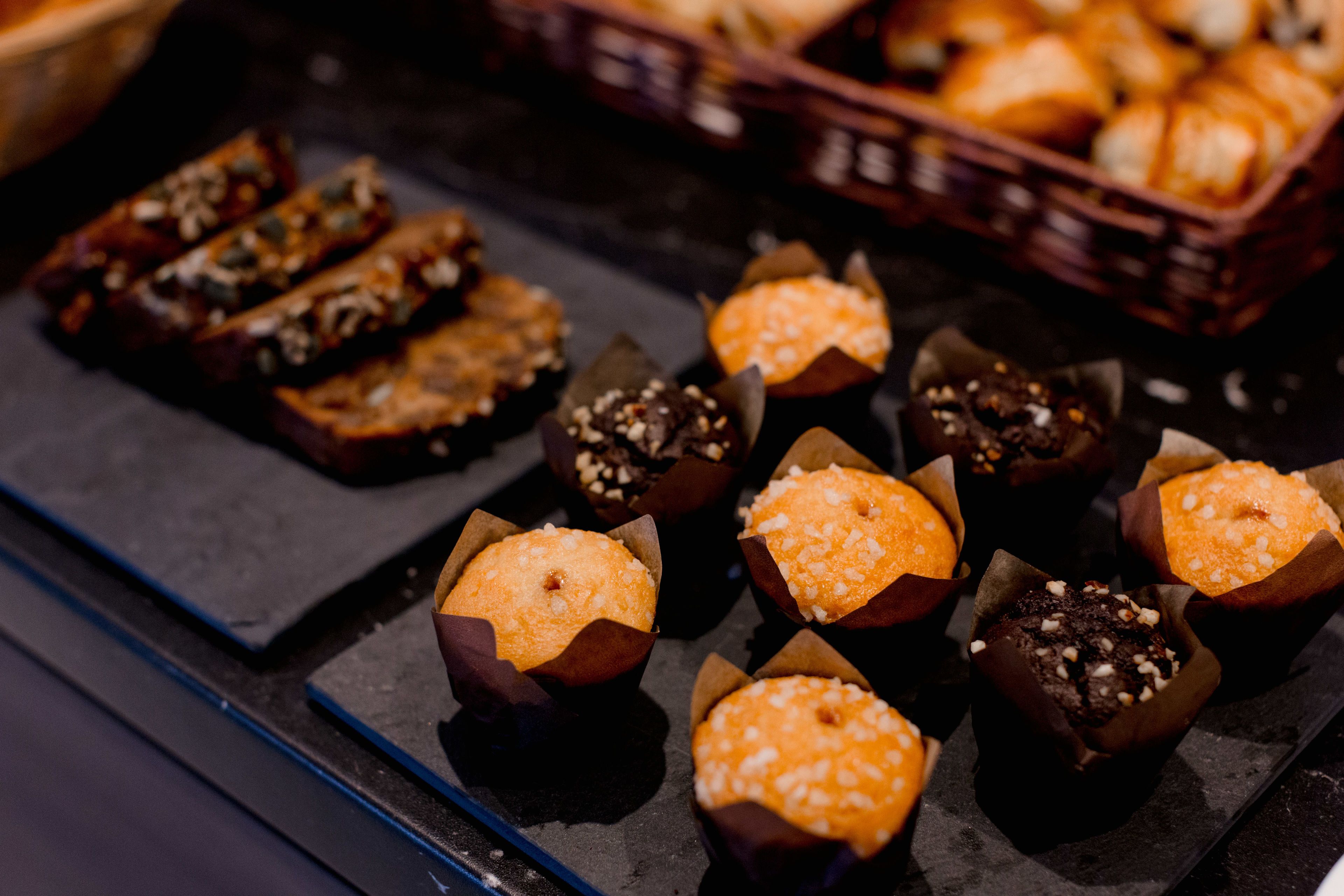 A tray of assorted baked goods, including muffins and pastries, on a dark surface.