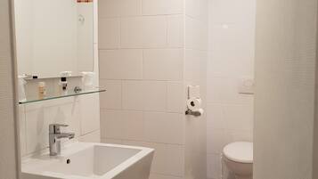 A bathroom with a white sink, mirror, and toilet.