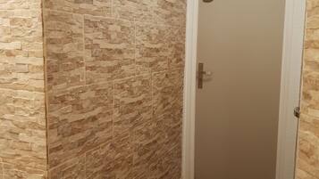 Un couloir avec un mur à texture et un plancher en bois. On peut voir une porte portant le numéro 523.