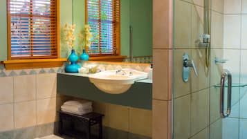 A bathroom with a sink, mirror, and shower.