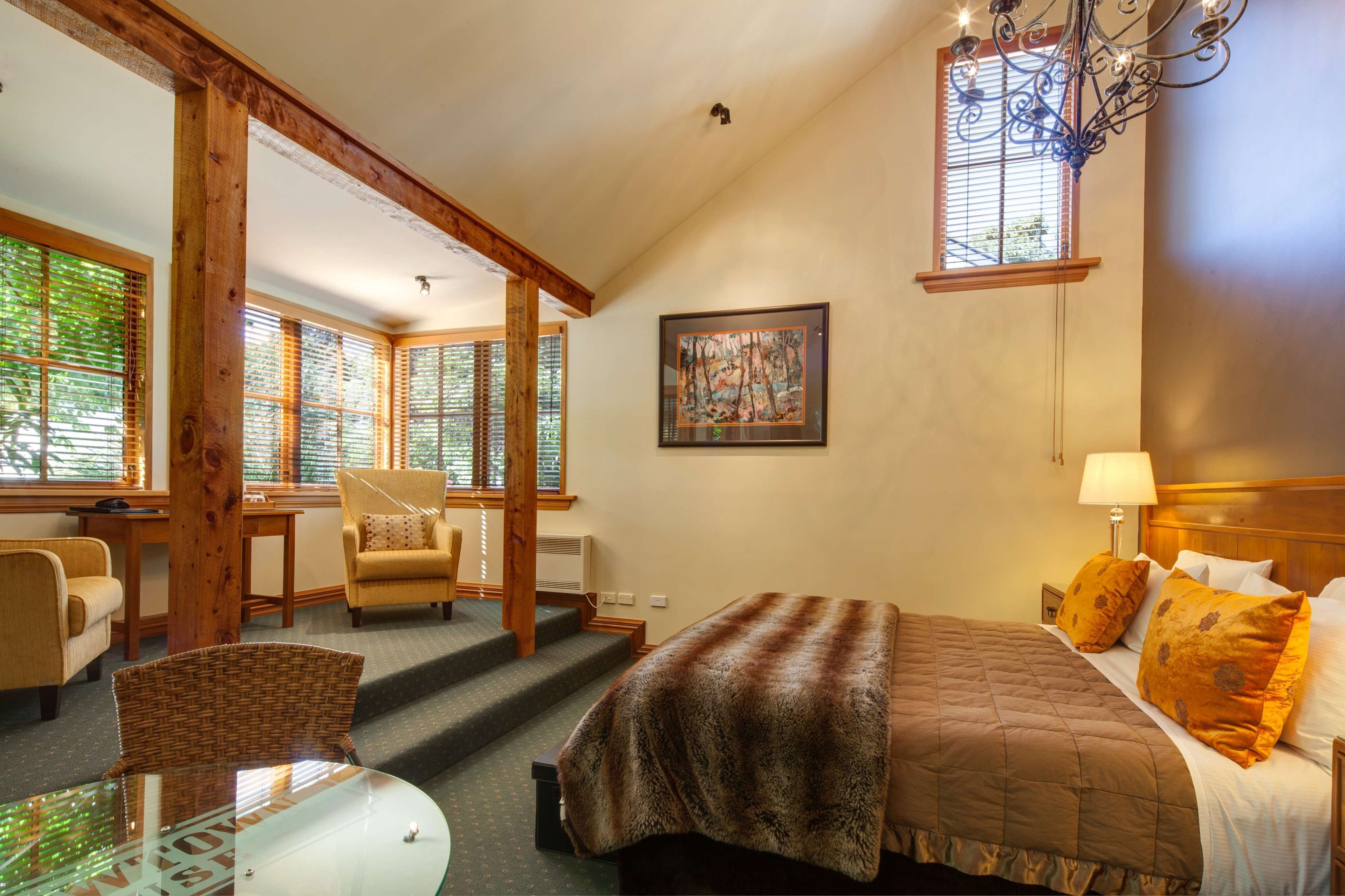 A bedroom with a bed, a chair, a table, and a staircase.