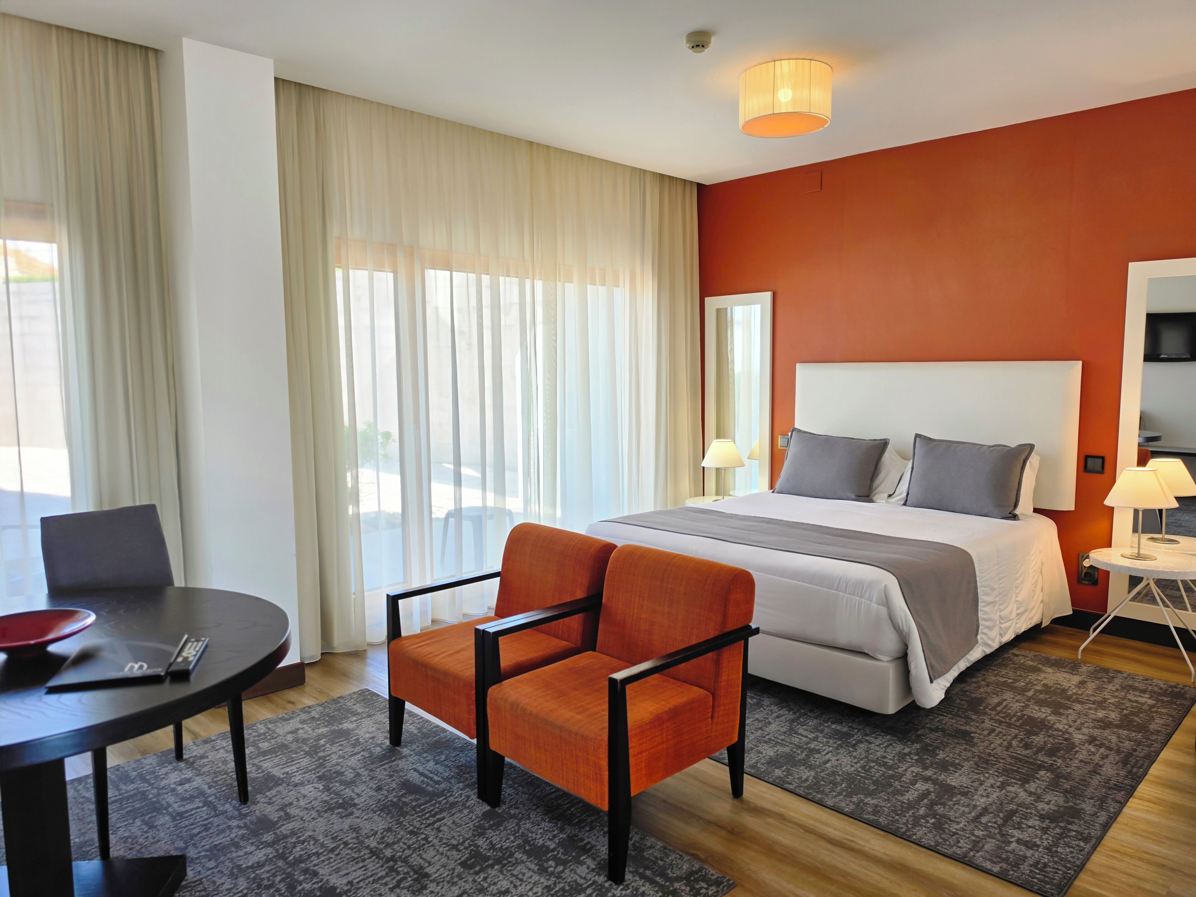 A hotel room with a bed, a desk, a chair, and a TV.