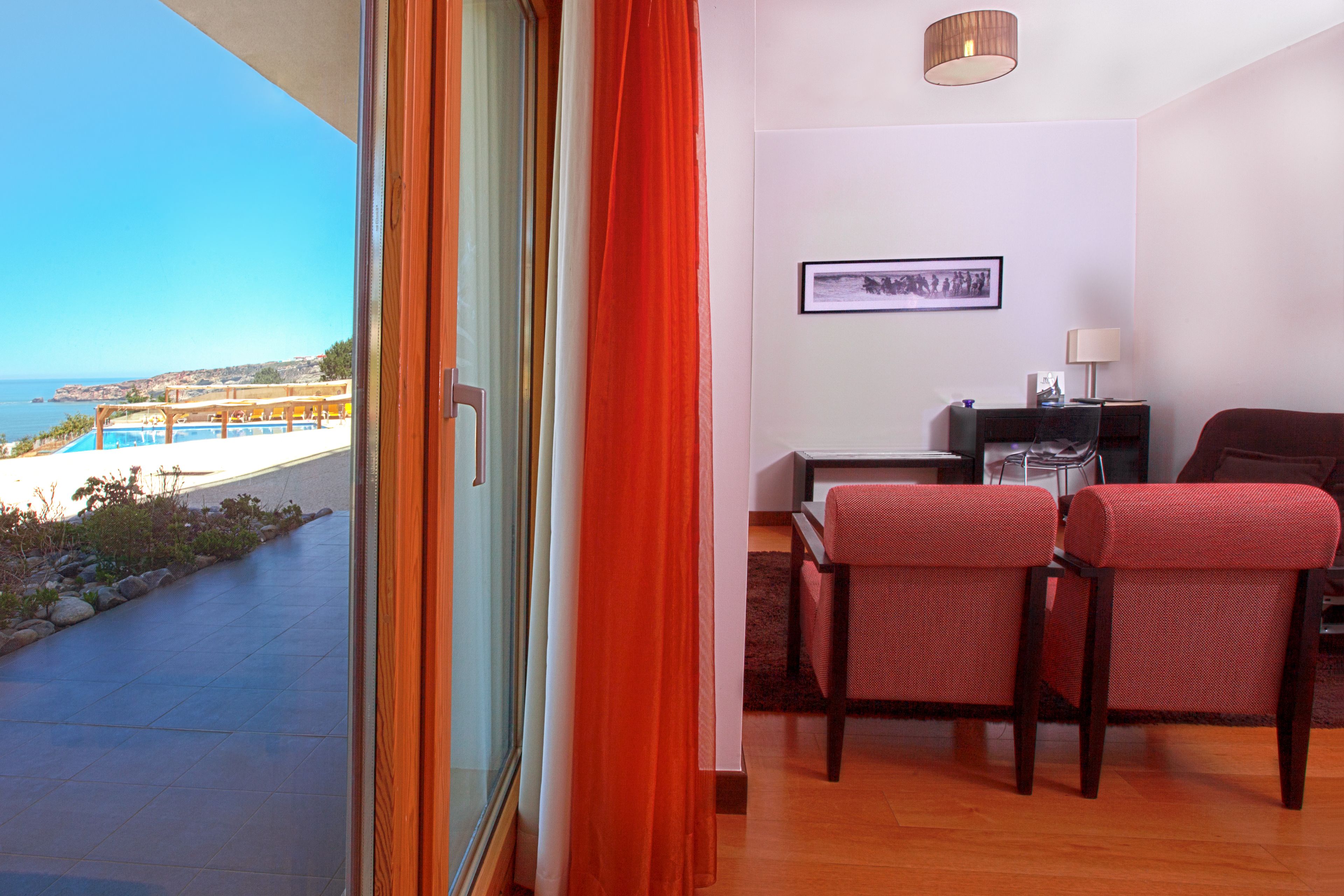 Una habitación con vistas al mar, un escritorio, dos sillas y una lámpara.