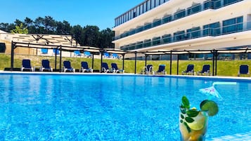 A swimming pool with lounge chairs and a glass of drink.