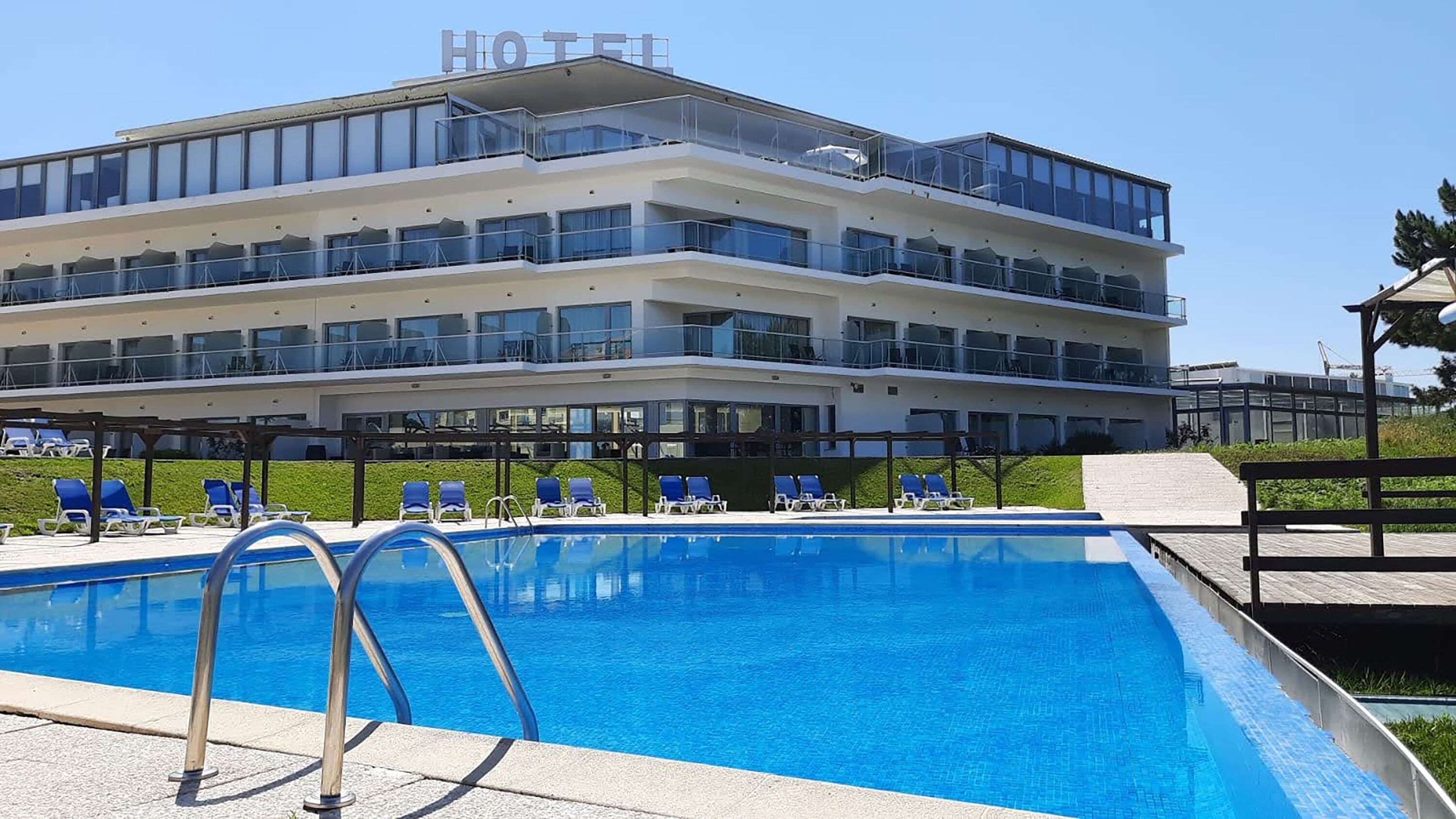 Un hotel con piscina, varios balcones y cielo despejado.
