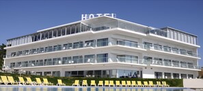 A multi-story hotel with a prominent "HOTEL" sign, balconies with glass railings, and a pool area with sun loungers. - Hotel Miramar Sul (Nazaré)