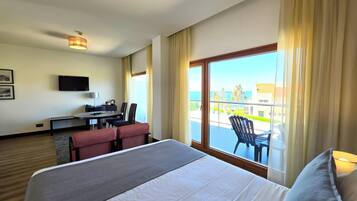 Ein Hotelzimmer mit Bett, Schreibtisch mit Stuhl, Fernseher und einem Balkon mit Blick.