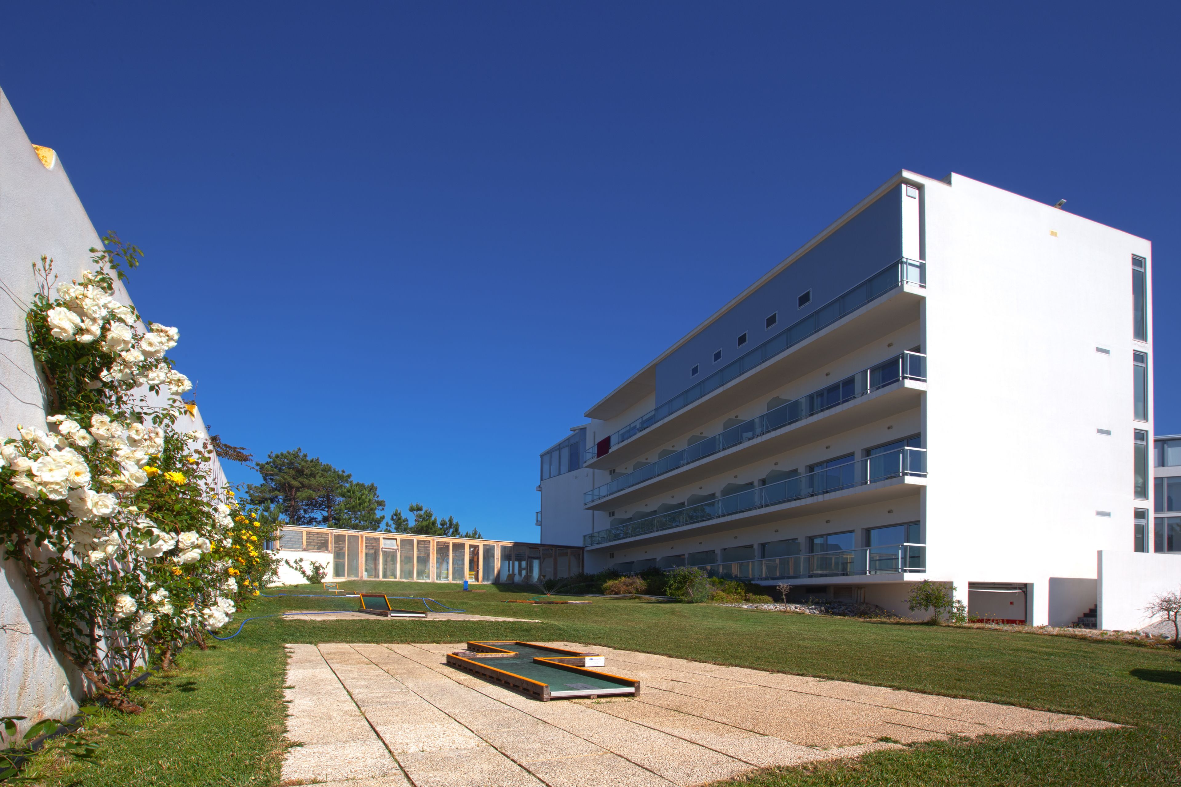 Un edificio moderno con numerosi balconi e un cortile con tavolino da biliardo.