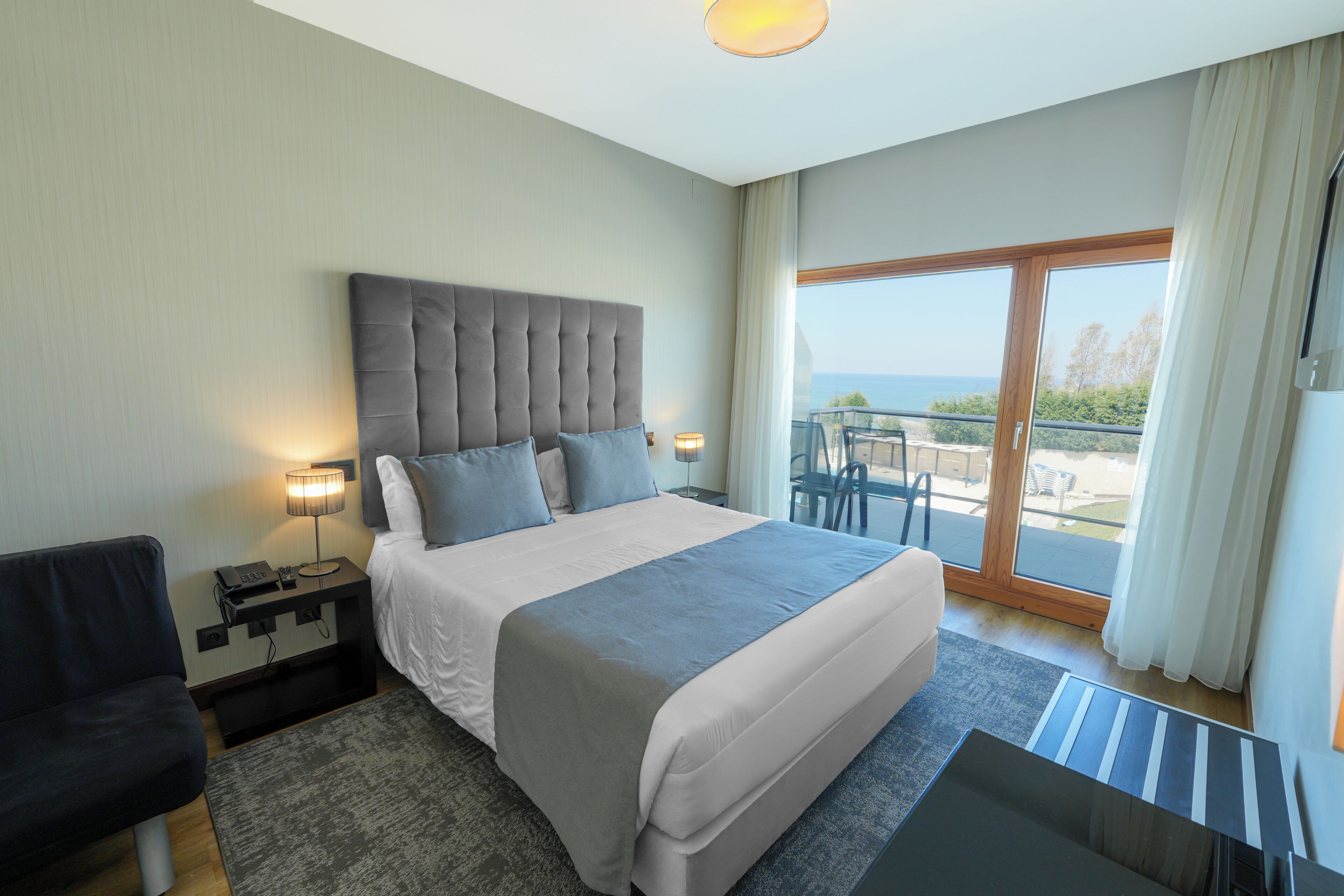 Une chambre d’hôtel avec un lit, un bureau, une chaise et un balcon offrant une vue.