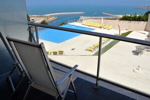 A balcony with a pool, yellow lounge chairs, and a view of the sea. - Hotel Miramar Sul (Nazaré)