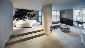 A modern bedroom with a bed, a seating area, and a staircase leading to an upper level. - The Screen (Kyoto)