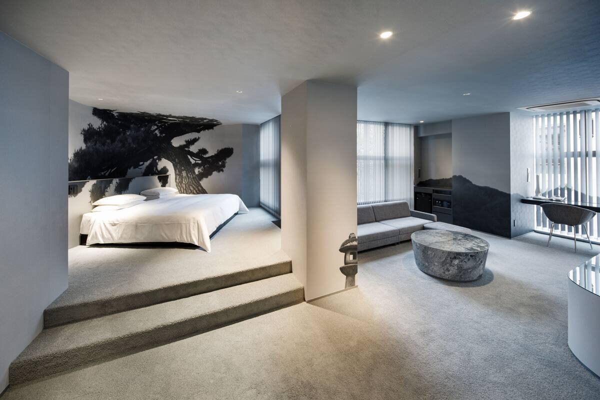 Une chambre moderne comprenant un lit, un coin salon et un escalier menant à un niveau supérieur.