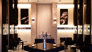 A modern bar area with a central bar, seating on both sides, and decorative wall art. - The Screen (Kyoto)