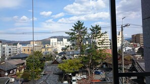Un pueblo japonés tradicional con casas de madera, una mezcla de edificios modernos y tradicionales, y una montaña al fondo.