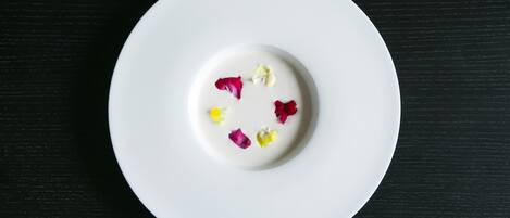 A white plate with a white substance and colorful flower petals on a black surface.