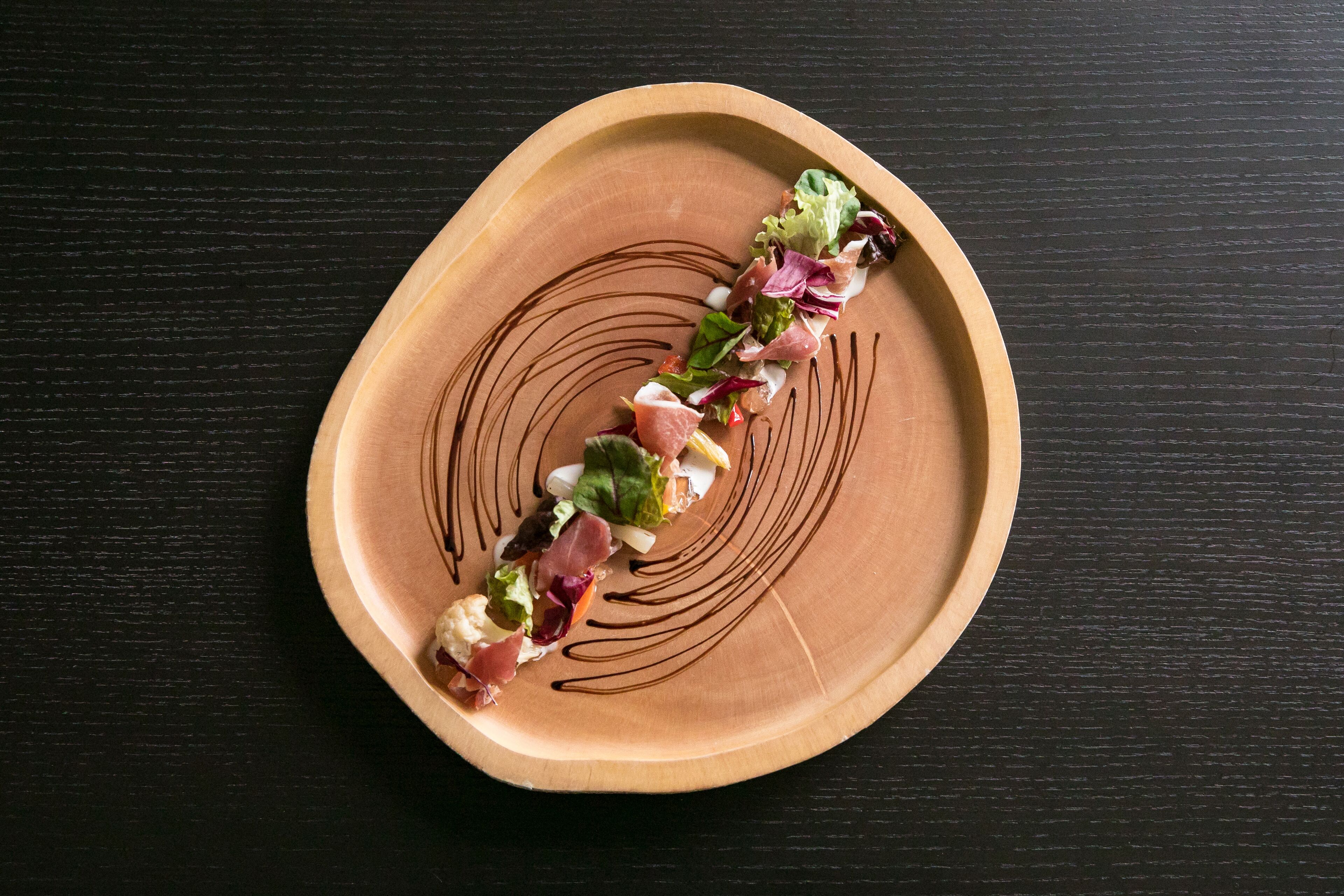 A wooden plate with a decorative design, containing a food arrangement.