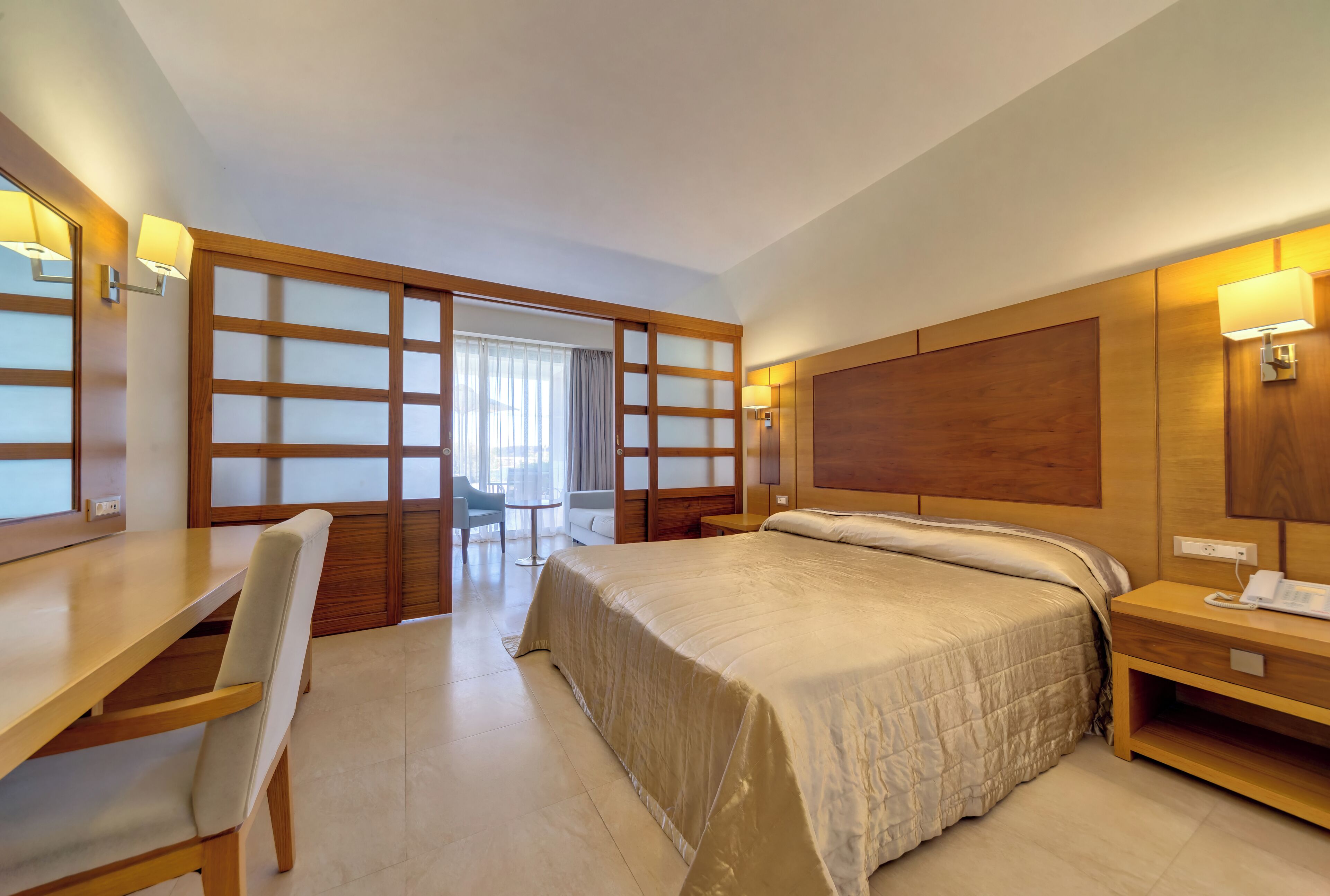 Une chambre d’hôtel équipée d’un lit, d’un bureau, d’une chaise et d’une porte coulissante donnant sur un balcon.
