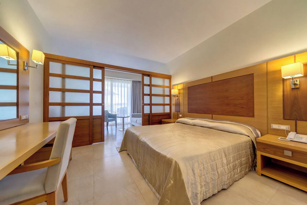 Une chambre d’hôtel équipée d’un lit, d’un bureau, d’une chaise et d’une porte coulissante donnant sur un balcon.