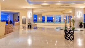 A modern lobby with a glass reception desk, seating area, and a decorative wall with blue accents. - Apollo Blue (Rhodes)