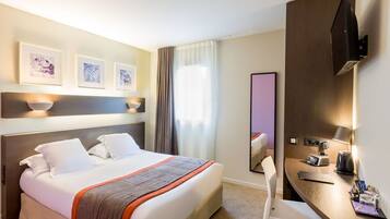 Habitación de hotel con una cama grande, un escritorio con silla, televisión de pantalla plana y cuadros en la pared.