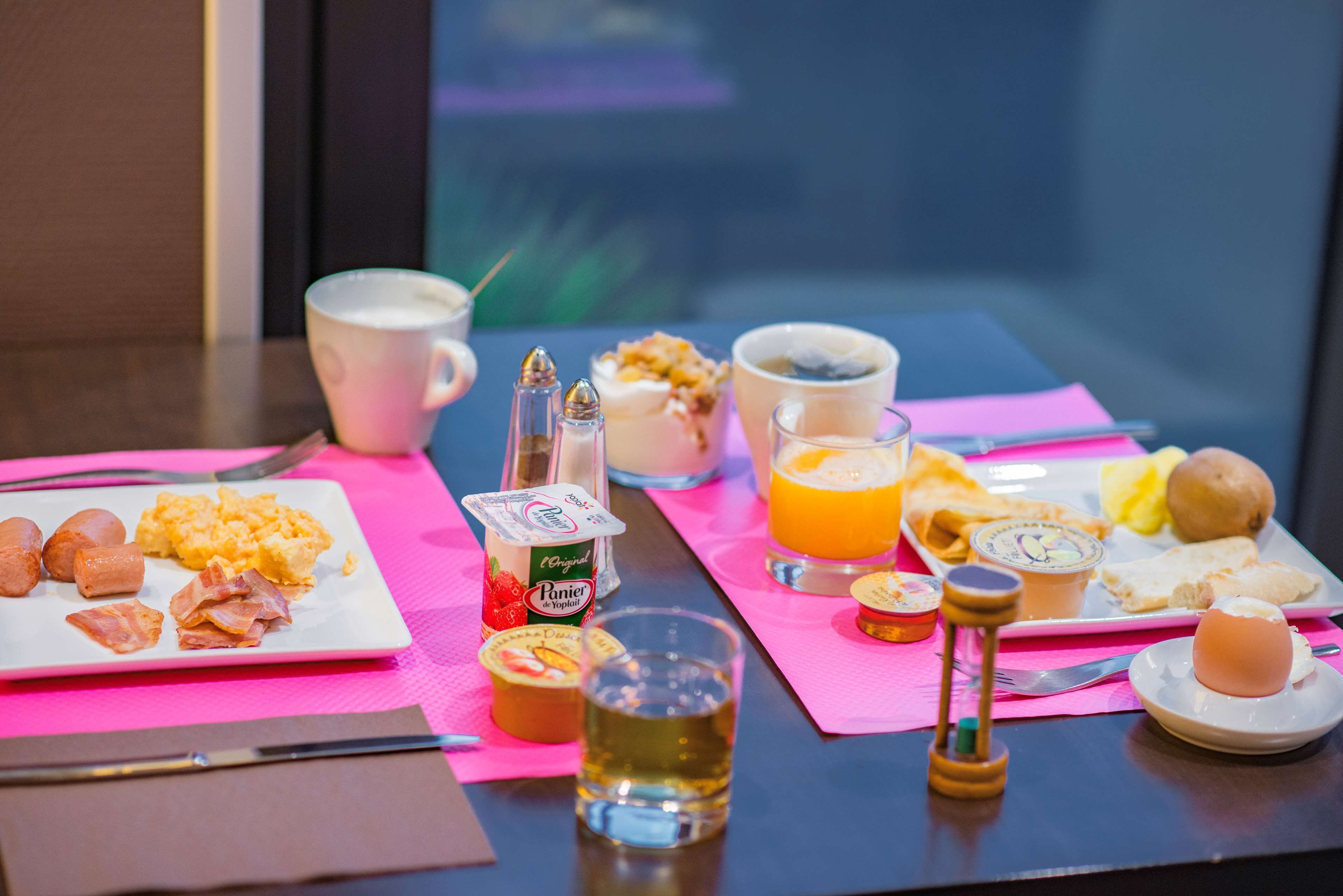 A breakfast table with plates of eggs, bacon, and toast, a glass of orange juice, and a cup of coffee.