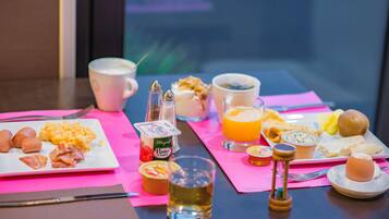 A breakfast table with plates of eggs, bacon, and toast, a glass of orange juice, and a cup of coffee.