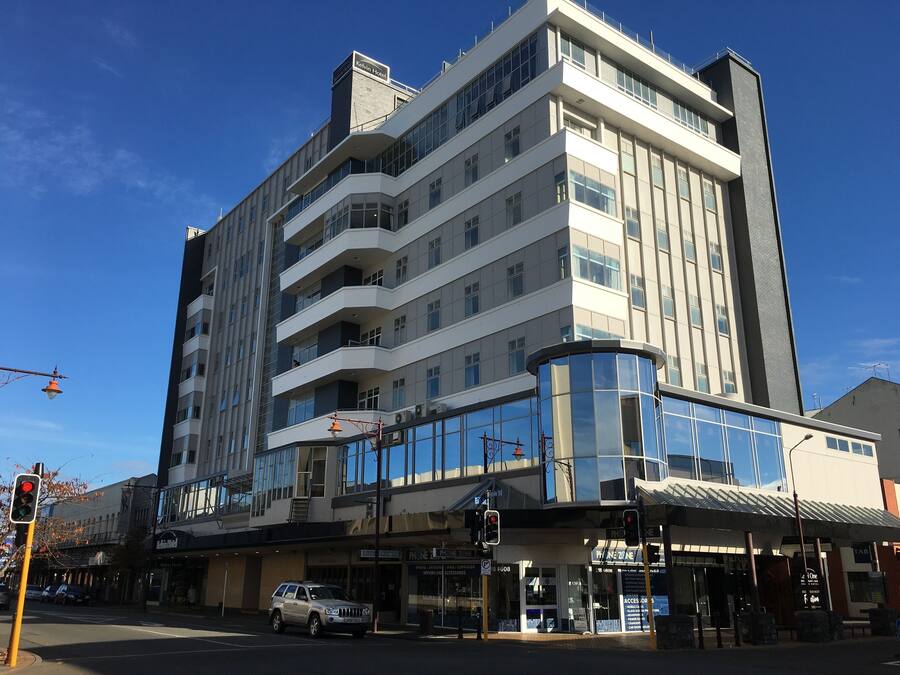 Un hotel de varios pisos con diseño moderno, que cuenta con balcones y grandes ventanales.