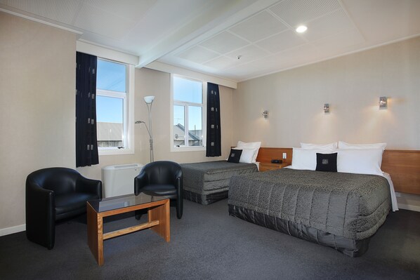 A hotel room with two beds, a desk, a chair, and a window. - Kelvin Hotel (Invercargill)