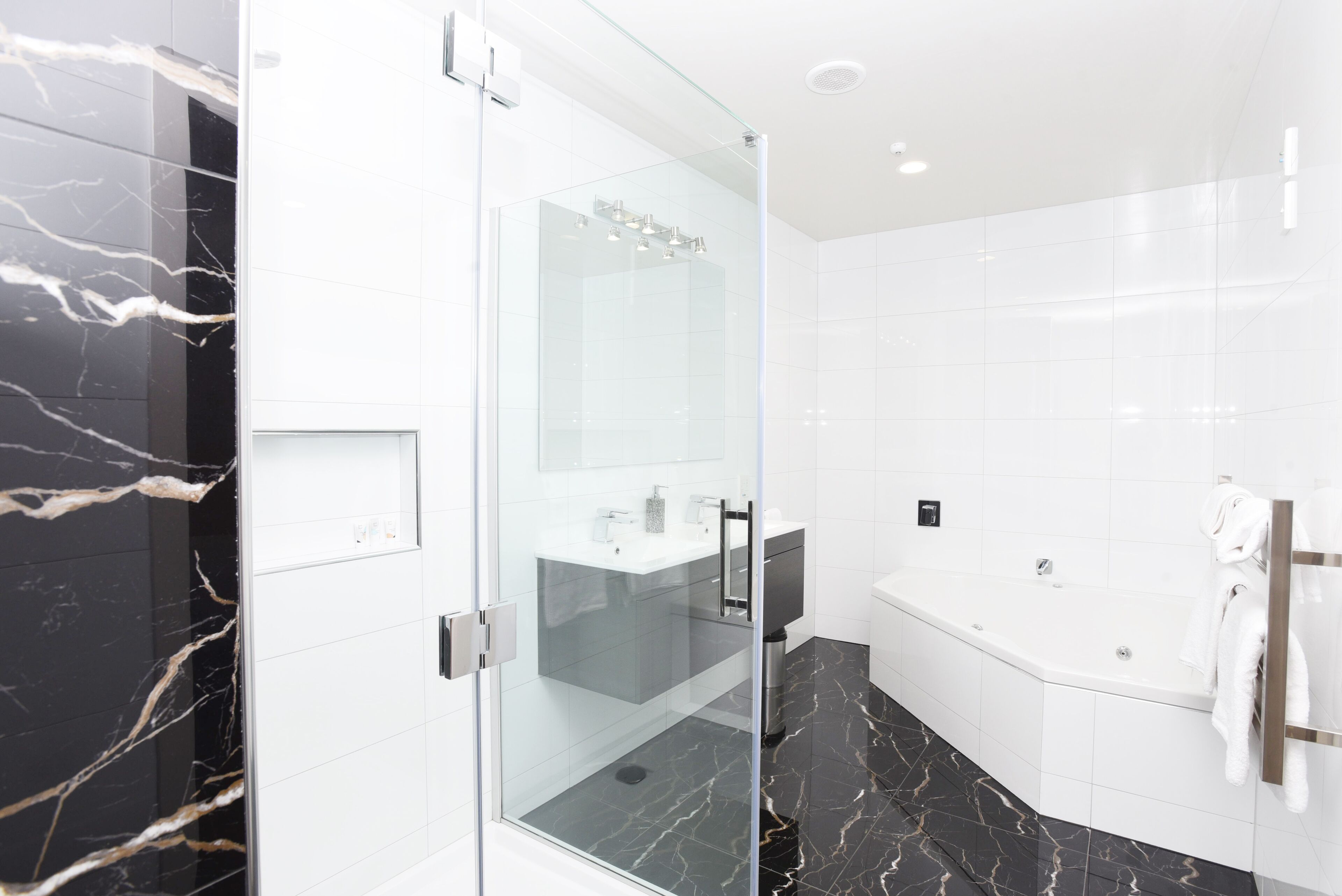 A modern bathroom with a glass-enclosed shower, a white sink, and a bathtub.